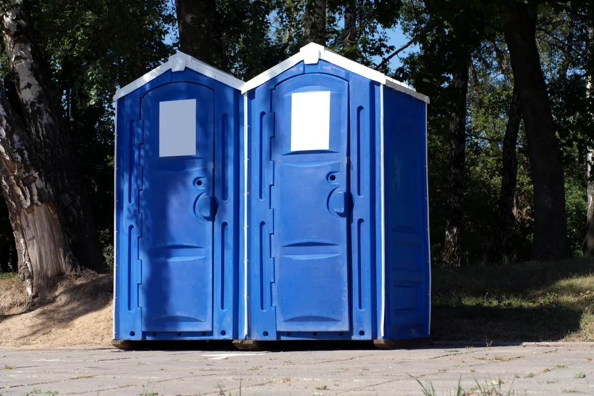 Two blue portable toilets positioned side by side in an outdoor setting, showcasing their compact design and functionality.